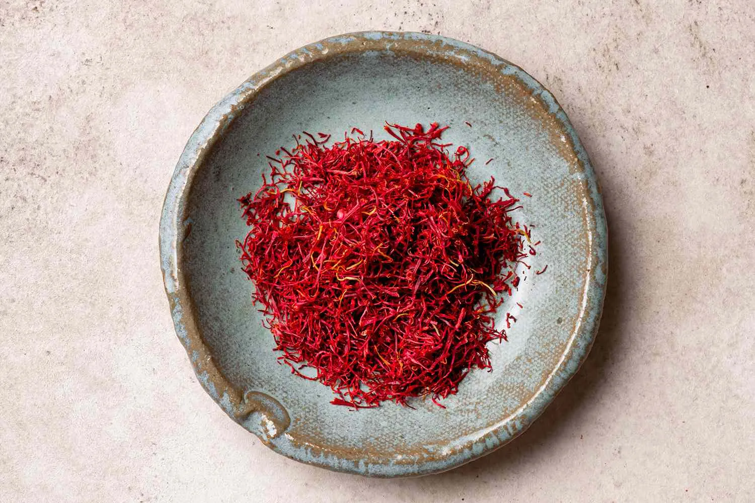 Serbuk saffron berkualiti tinggi dalam mangkuk, menunjukkan warna merah tua yang kaya dan tekstur halus, sering digunakan dalam masakan dan perubatan.